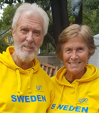 Christine och Roffe utomhus i gula tröjor, tätt intill varandra och leende mot kameran.