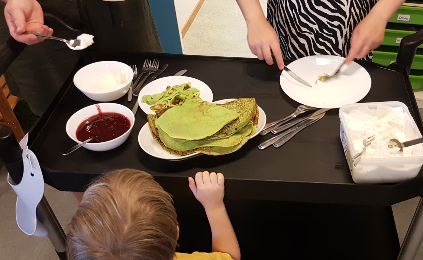 En trave gröna pannkakor på ett fat, med sylt och grädde bredvid på serveringsvagnen.